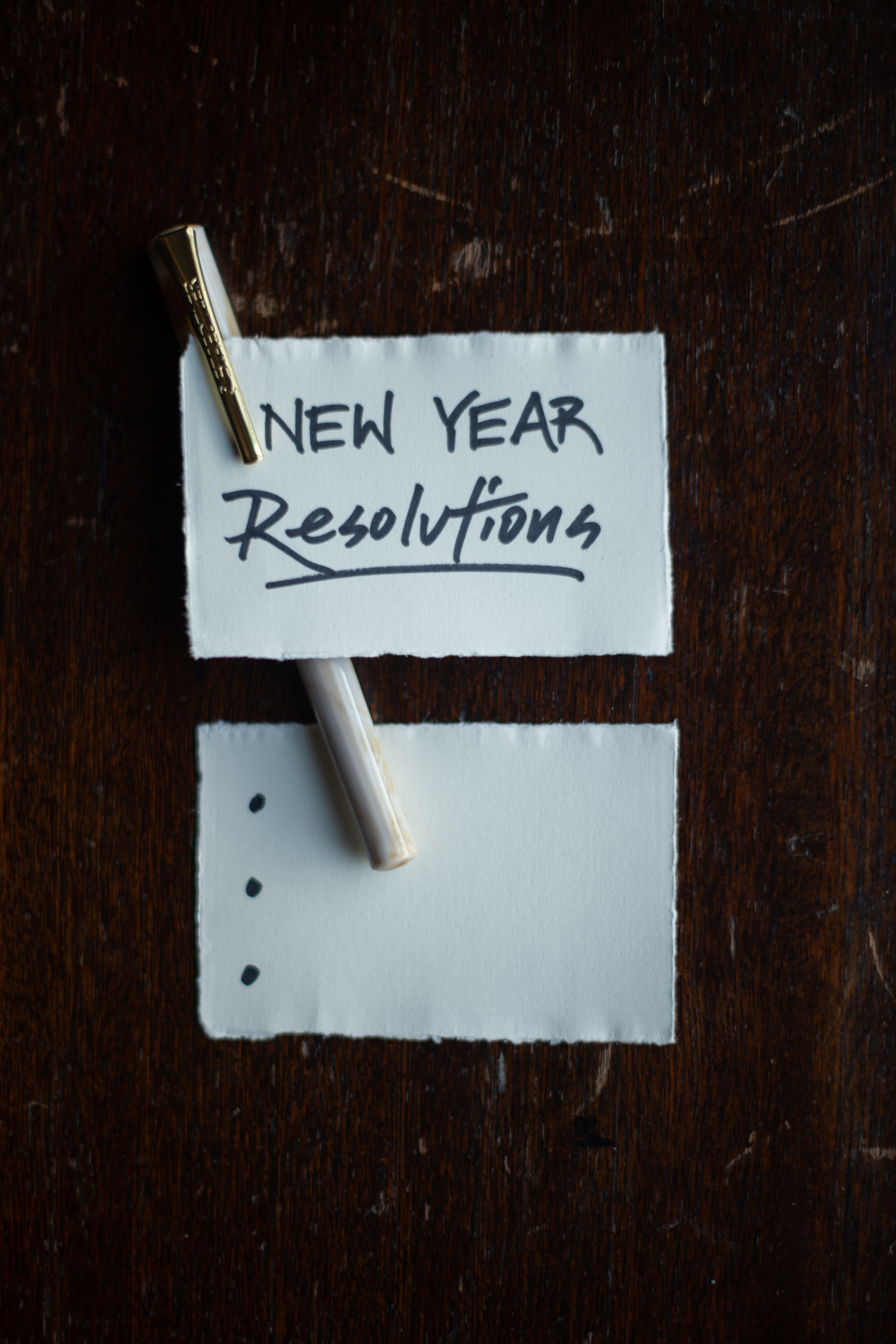 A piece of papper with a pen attached to it that states "New Year Resolutions.